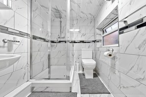 Ein modernes Badezimmer mit Duschkabine aus Glas, Toilette und Waschbecken.