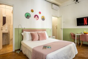 Ein Hotelzimmer mit Bett, Fernseher, Schreibtisch mit Stuhl und einer Wand mit Dekotellern.