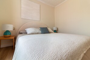 Ein Schlafzimmer mit einem Bett, zwei Nachttischen, einer Lampe und einem Wandbild.