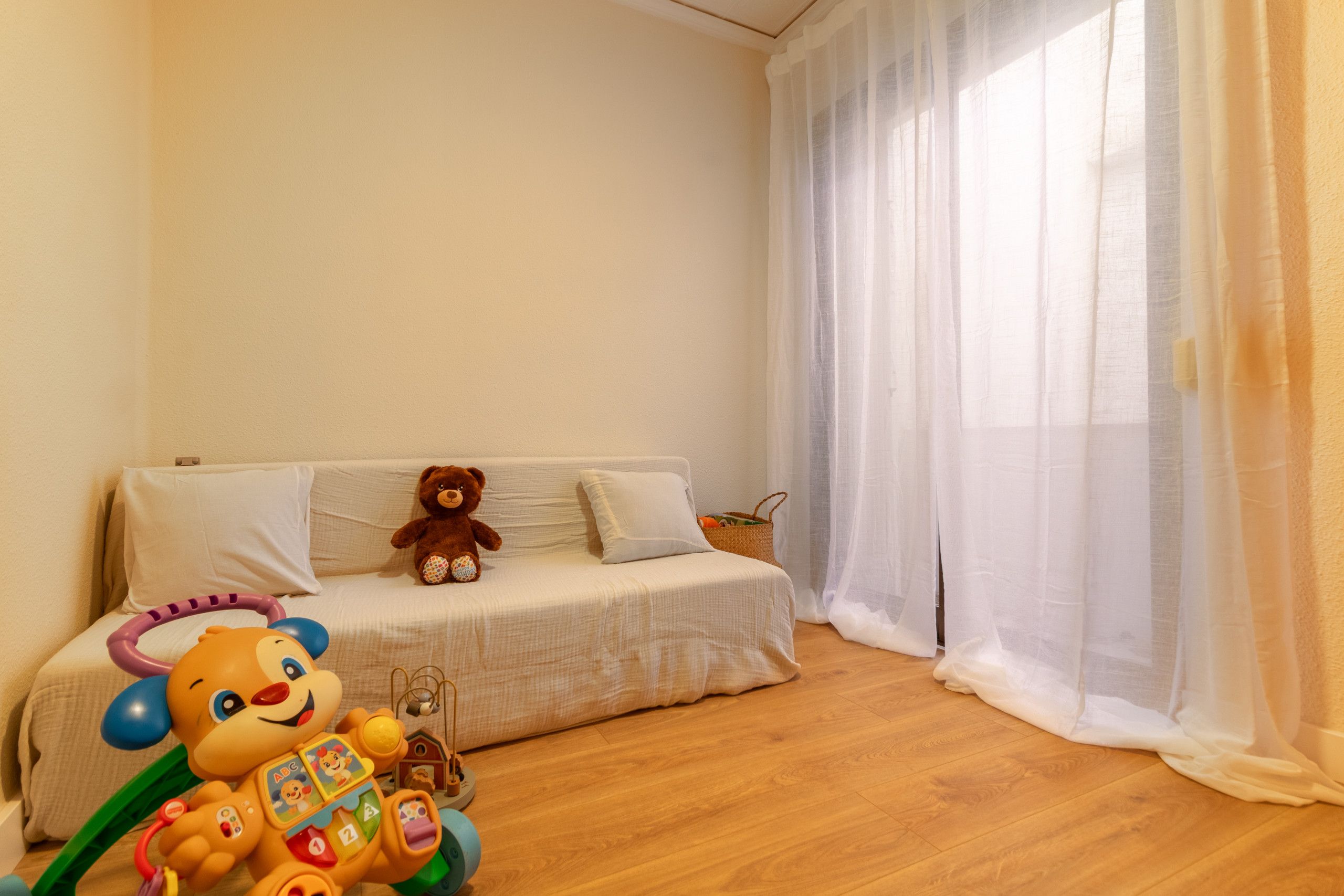 Une pièce chaleureuse avec un canapé, un ours en peluche et un jouet.