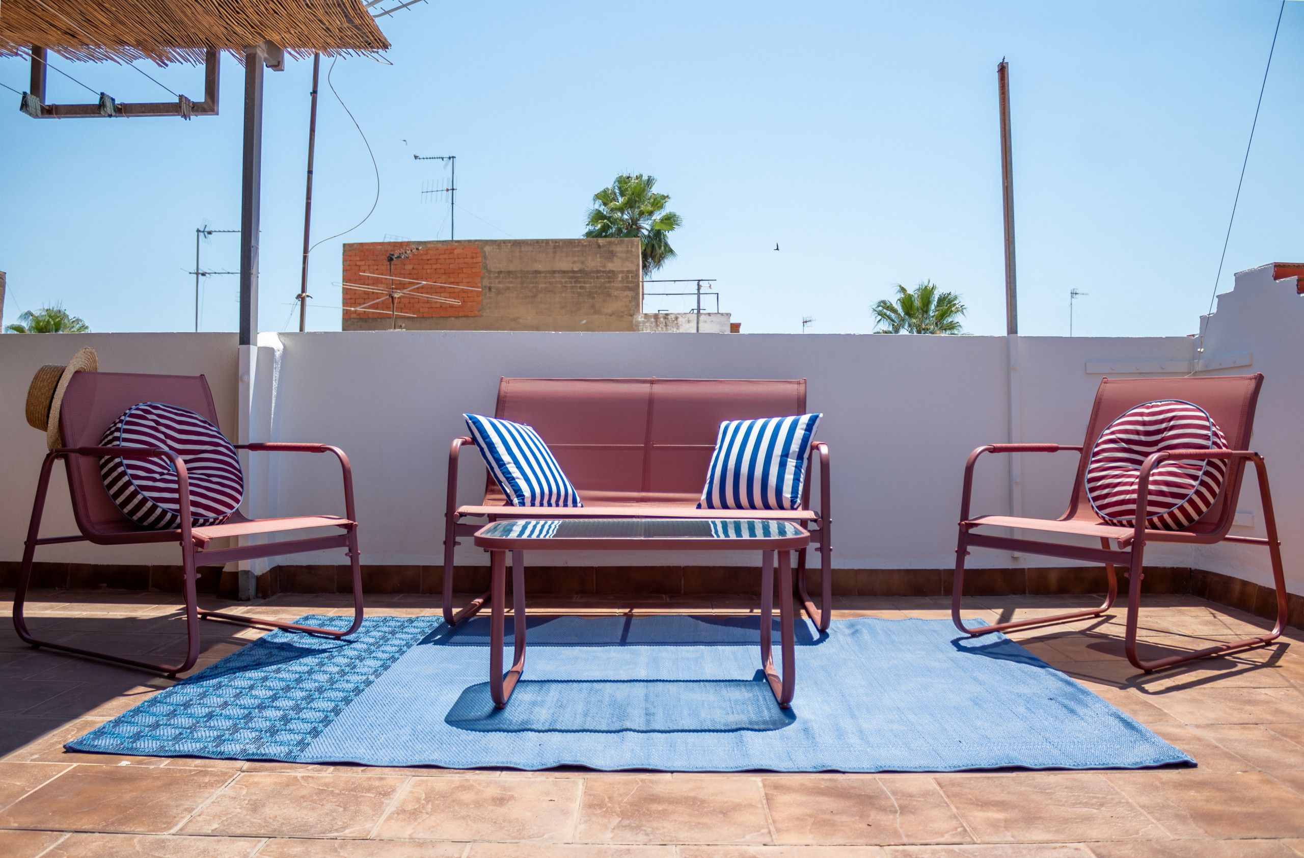 Een terras met twee loungestoelen, een bank en een blauwe mat.