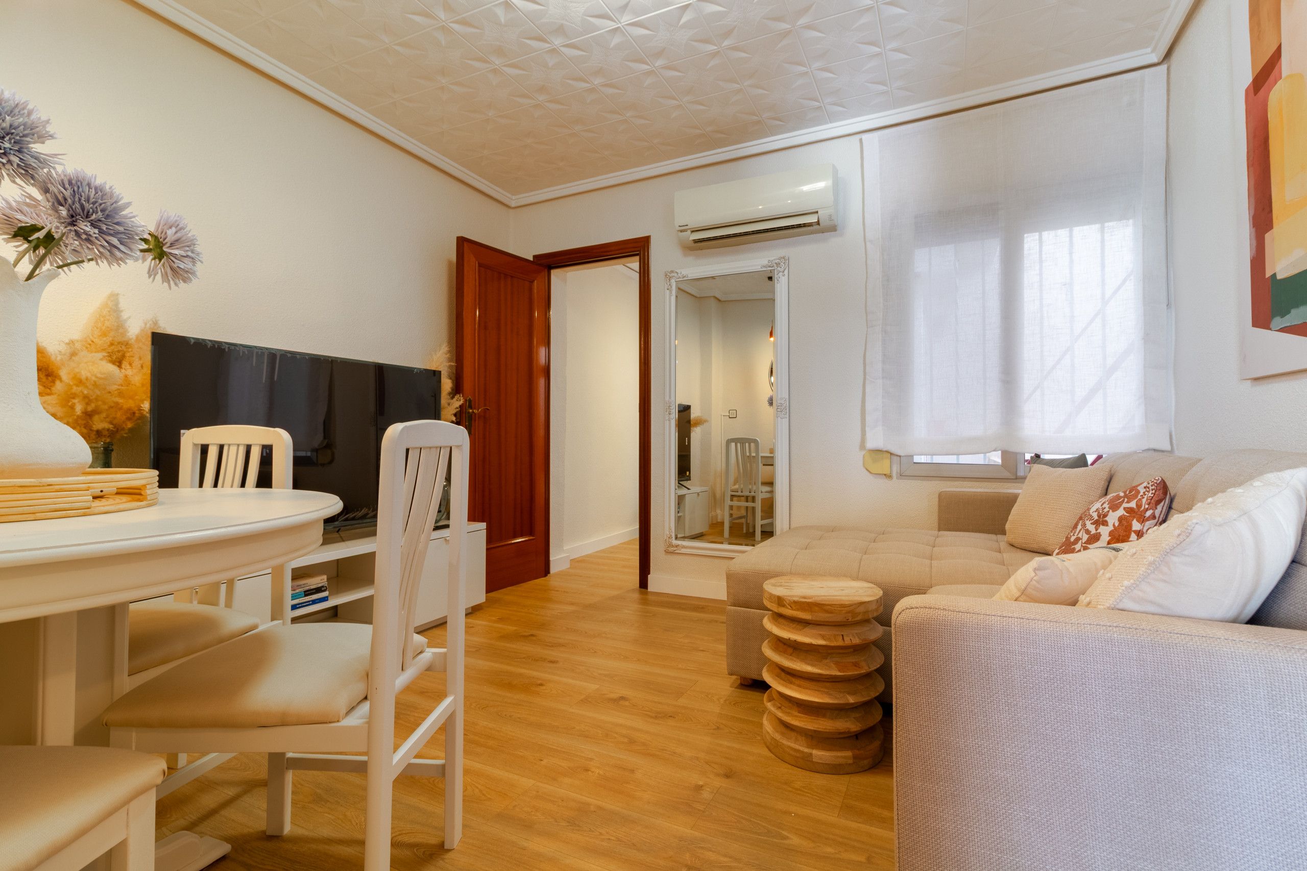 Un salon moderne avec un canapé, une table à manger et des chaises, un téléviseur et un plancher en bois.