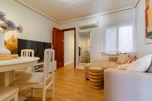 Ein modernes Wohnzimmer mit einer Couch, einem Esstisch mit Stühlen, einem Fernseher und Holzboden.