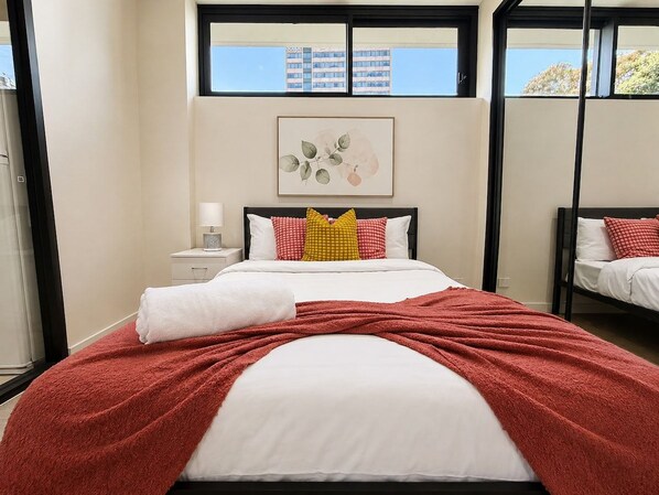 Una habitación de hotel con una cama, una mesita de noche, un ventanal y una obra de arte colgada en la pared.