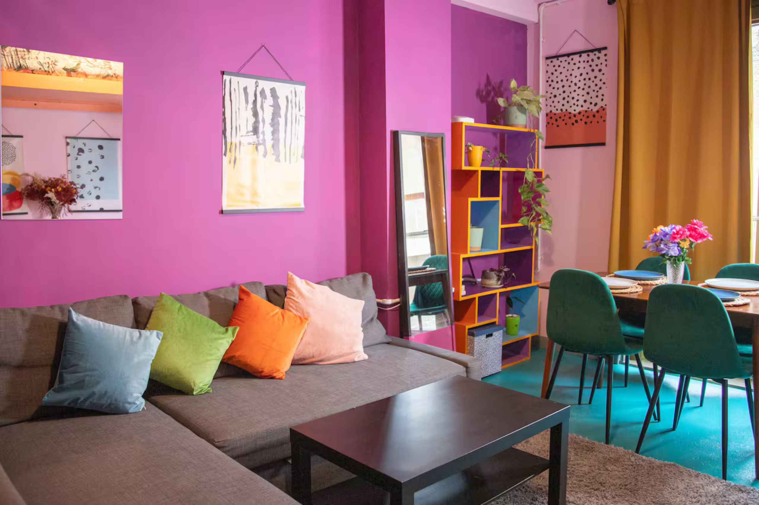 A modern living room with a grey sofa, colorful cushions, a coffee table, and a vibrant purple wall.