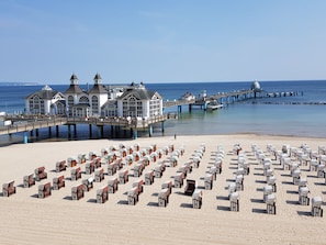 A beach with rows of beach chairs and a pier with buildings. - Holiday Apartment With 2 Bedrooms (Sellin)