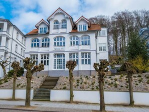 A multi-story building with a classic architectural style, featuring a prominent entrance with steps and a gated driveway. - Holiday Apartment With 2 Bedrooms (Sellin)