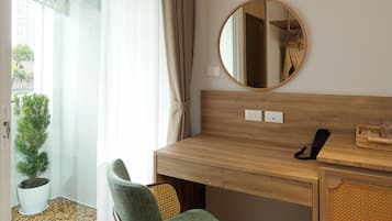 A room with a wooden desk, a chair, a round mirror, an air conditioning unit, and a potted plant.