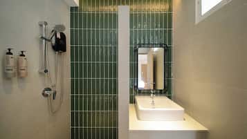 A bathroom with a shower, a sink, and two bottles of shampoo.