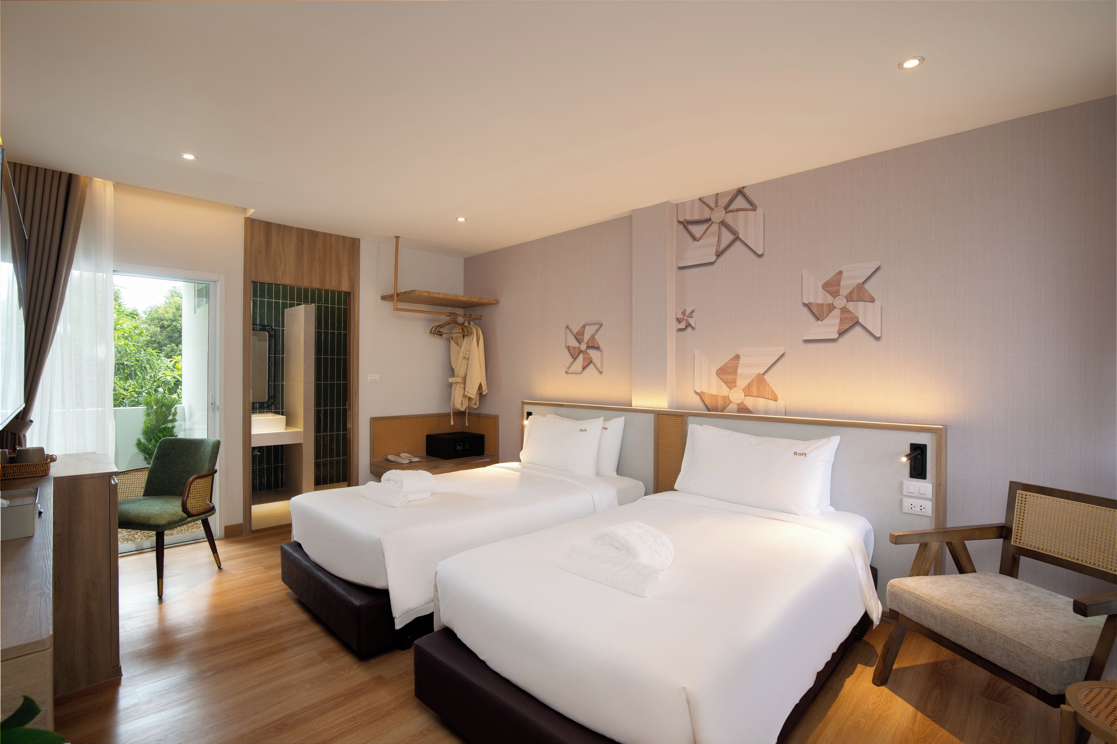 A hotel room with two beds, a sitting area with a chair, a small table, and a window with curtains.