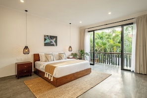 A bedroom with a large bed, bedside tables, a painting, and a view of greenery through a sliding door. - Cozy 4BR Villa Shalom Near Canggu Beach (Canggu)