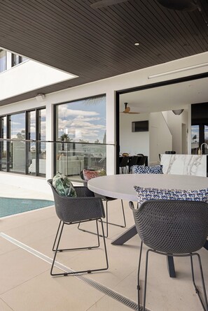 Un espace extérieur aménagé pour les repas, avec une piscine, un mobilier moderne et une vue sur la ville.