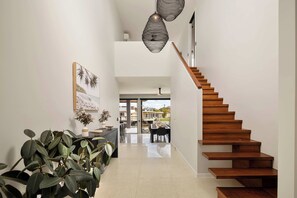 Un intérieur moderne avec un escalier en bois, un coin repas et une vue sur l’extérieur.