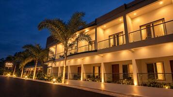 Un hotel de varios pisos con un diseño moderno, con balcones y una fachada bien iluminada.
