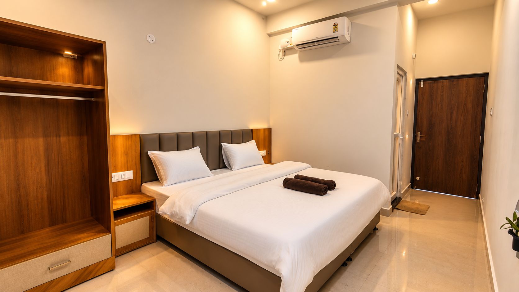 Habitación de hotel con cama, armario, aire acondicionado y puerta.
