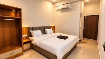 Habitación de hotel con cama, armario, aire acondicionado y puerta.