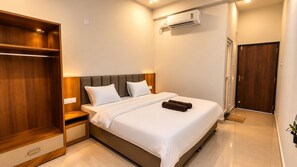 A hotel room with a bed, a wardrobe, an air conditioning unit, and a door. - ORO Gokarna (Kumta)
