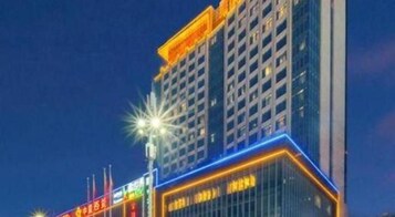 Un edificio de hotel de varios pisos con señalización iluminada y un diseño arquitectónico moderno.
