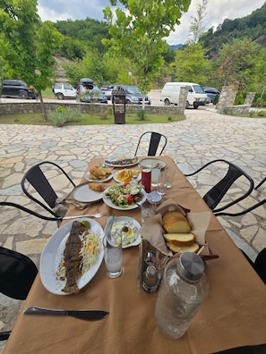 An outdoor dining table with various dishes, a bottle, and a salt shaker. - Oniropagida House in Beautiful Nature (Central Tzoumerka)