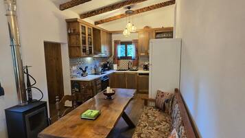 A cozy interior with a wooden dining table, bench seating, a kitchen area, and a visible chimney.