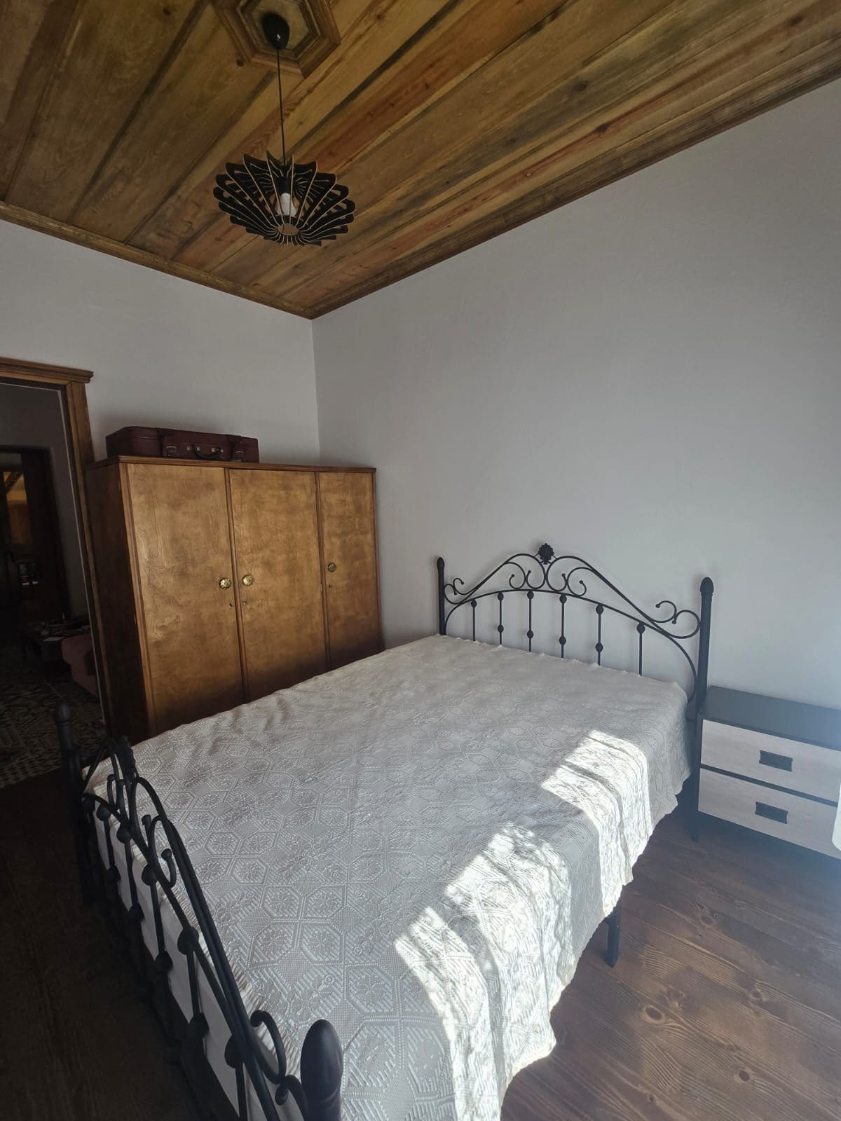 Un dormitorio con cama, armario y ventilador de techo.