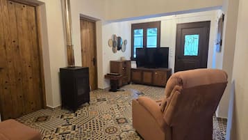 Un soggiorno con pavimento a motivi, televisore, divano e soffitto in legno.