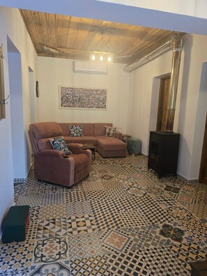 A living room with a patterned floor, a sofa set, a ceiling fan, and a television. - Oniropagida House in Beautiful Nature (Central Tzoumerka)