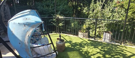 A garden with artificial grass, a swing set, and a pergola structure.