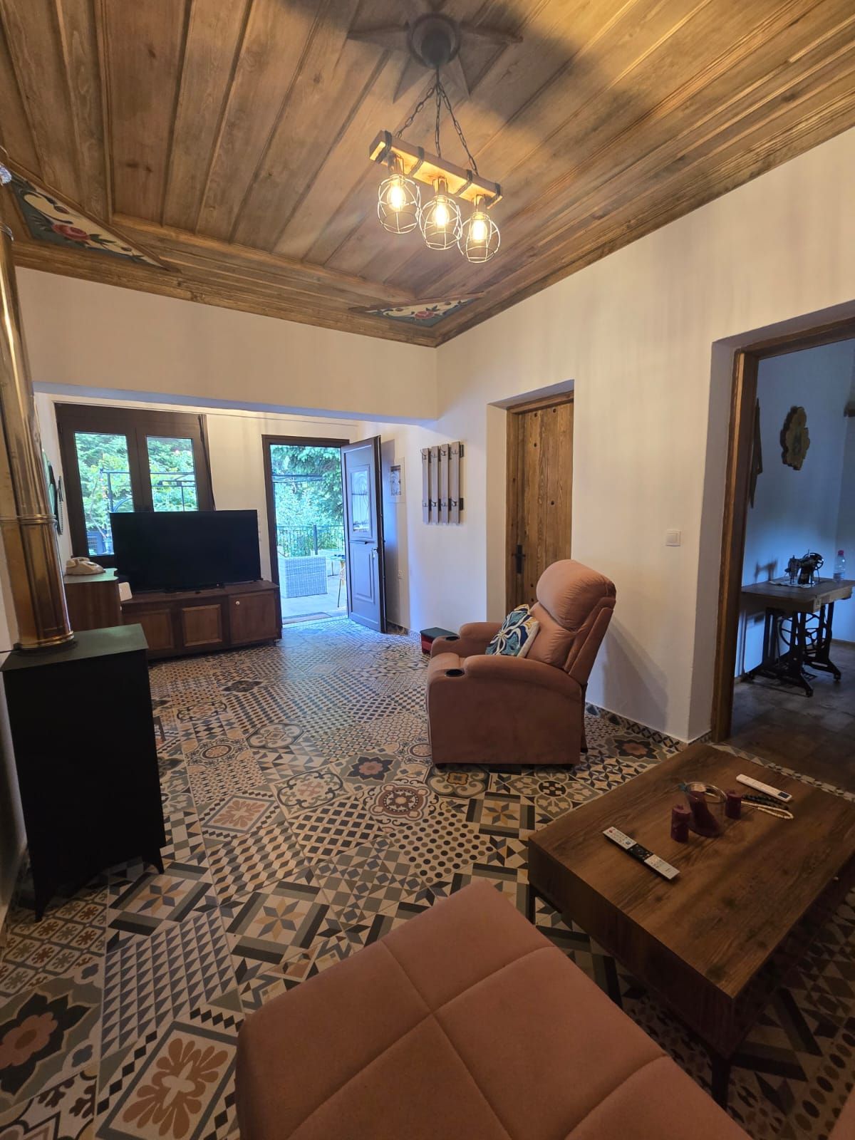 Un'ampia zona giorno con pavimento decorato, un divano confortevole, un tavolino in legno e una televisione sullo sfondo.