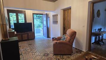 Un'ampia zona giorno con pavimento decorato, un divano confortevole, un tavolino in legno e una televisione sullo sfondo.