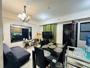 Una sala de estar moderna con comedor, sofá, televisor y dispensador de agua.