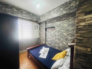 Una habitación con cama, ventana con vistas y pared de piedra.