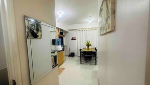 A hallway leading to a dining area with a table and chairs, a kitchen area with cabinets, and a wall with a 'love! HOME' sign. - Spacious Davao City Apartment 3 Bedrooms, Pool, and Pine Trees (Davao City)