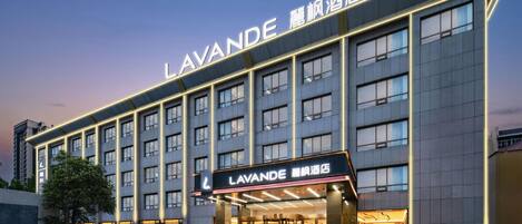 A hotel with a modern facade, multiple floors, and a prominent entrance with illuminated signage.