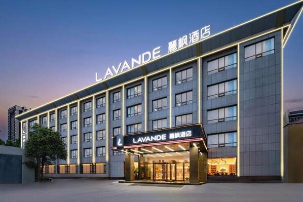 Een hotel met een moderne gevel, meerdere verdiepingen en een opvallende entree met verlichte signage.