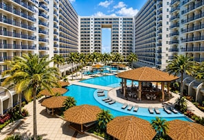 Ein Resort mit einem zentralen Pool, Liegebereichen und mehreren Hochhäusern.