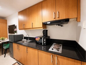 Eine moderne Küche mit Holzausstattung, einer schwarzen Arbeitsplatte, einer Kaffeemaschine, einem Toaster und einem Herd.