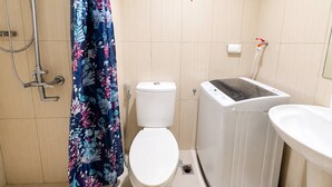 Een badkamer met toilet, een wasmachine en een douche.
