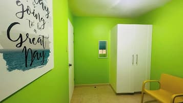 A hallway with a green wall, a white door, a bench, and a wardrobe.
