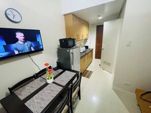 A compact living space with a dining area, kitchenette, and a TV mounted on the wall. - Fancy 1Br Condo Front of MOA IKEA at Shell  ResidencesTower B (Pasay)