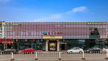 A hotel with a modern facade, a visible entrance, and a parking area in front.