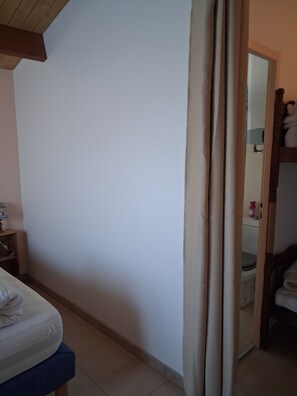 Ein Schlafzimmer mit einem Bett, einem Holz-Kopfteil, einem Nachttisch und einem durch eine Tür einsehbaren Badezimmer.