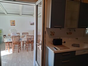 A kitchen with a toaster, a remote control, and a countertop. There is a dining area with wooden chairs and a table. - A 5-minute walk from the beach and the village of Les Boucholeurs. Perfect for families! (Châtelaillon-Plage)