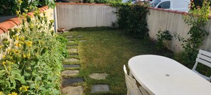 A garden with a stone path leading to a white table and chair. - A 5-minute walk from the beach and the village of Les Boucholeurs. Perfect for families! (Châtelaillon-Plage)