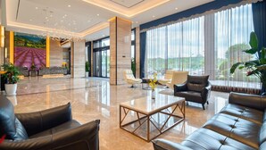 A spacious lobby with a reception desk, seating area, and large windows offering a view of the outdoors. - Lavande Hotel (Ganzhou)
