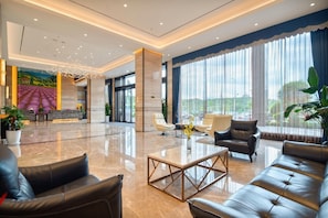 A spacious lobby with a reception desk, seating area, and large windows offering a view of the outdoors. - Lavande Hotel (Ganzhou)