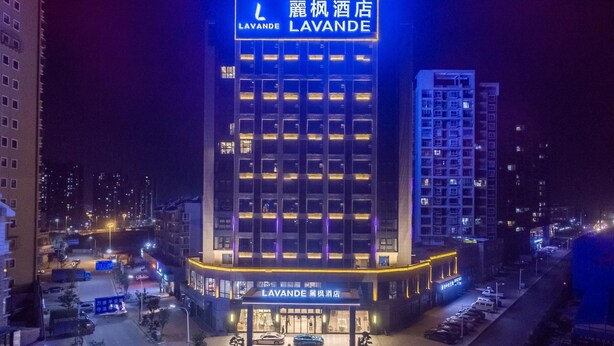 A hotel with a prominent sign, multiple floors, and a parking area. - Lavande Hotel (Ganzhou)