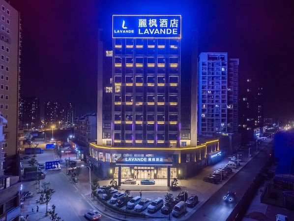 A hotel with a prominent sign, multiple floors, and a parking area. - Lavande Hotel (Ganzhou)