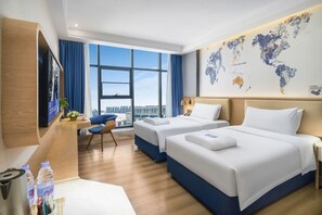 Habitación de hotel con dos camas, un escritorio con silla, un ventanal grande y un mapa del mundo en la pared.