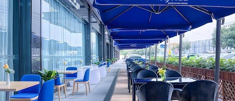 An outdoor seating area with blue umbrellas, tables, and chairs.